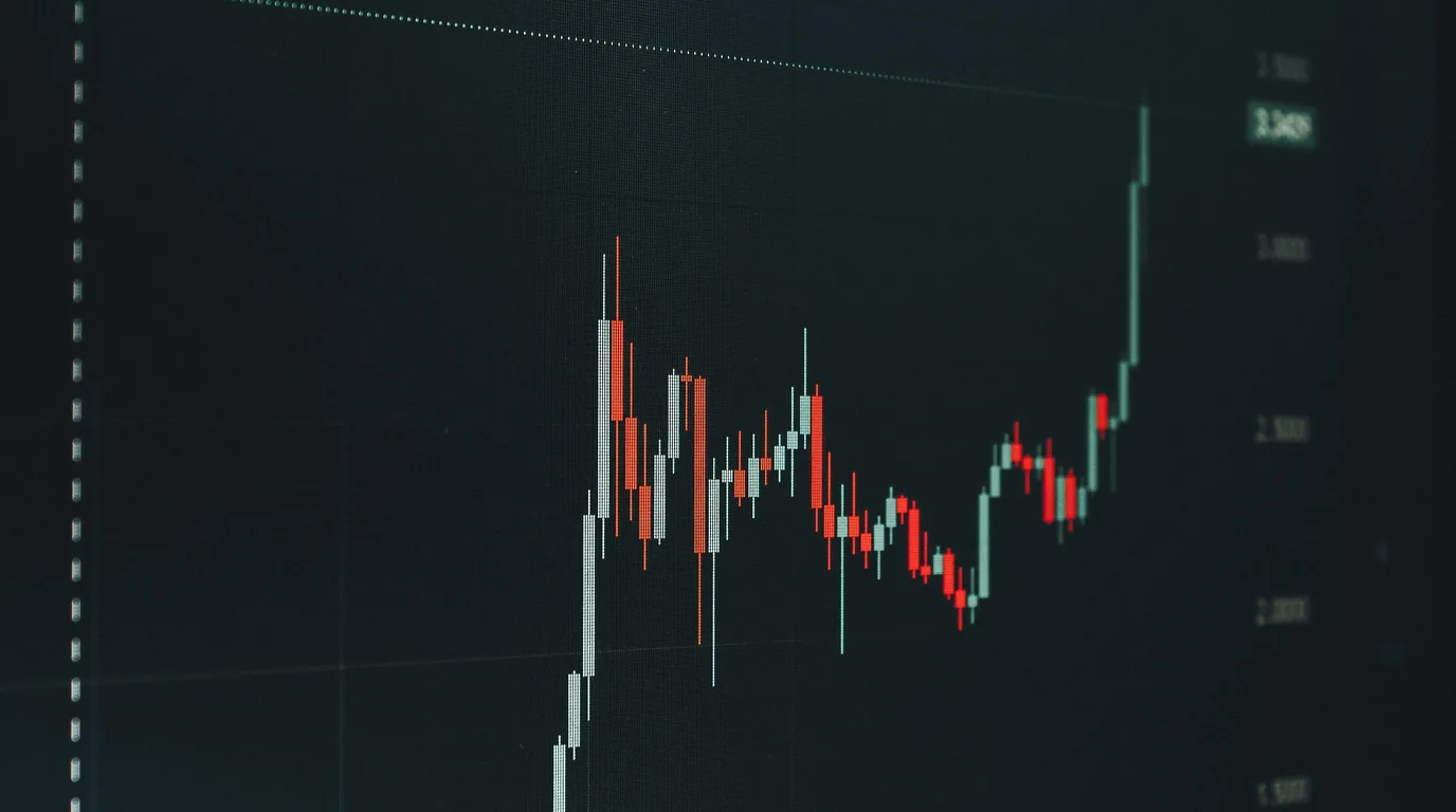 A darkened screen showing a red and white candlestick chart falling away then spiking to a new high